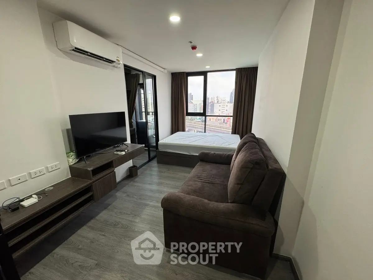 Modern studio apartment with city view, featuring cozy living area and large windows.