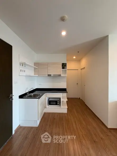 Modern kitchen with sleek cabinetry and wood flooring in a compact apartment
