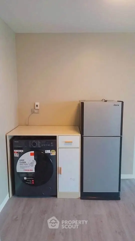 Modern laundry area with washing machine and compact fridge in a minimalist interior.