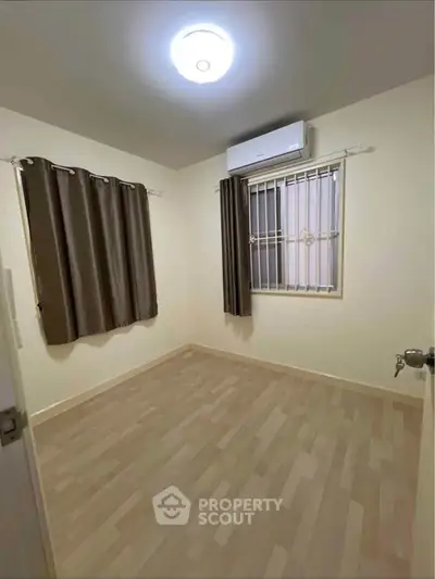 Cozy empty bedroom with wooden flooring and air conditioning, ready for personalization.
