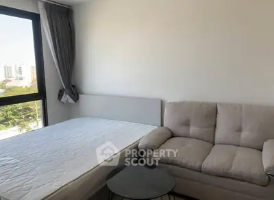 Cozy bedroom with a comfortable sofa and large window offering city views.