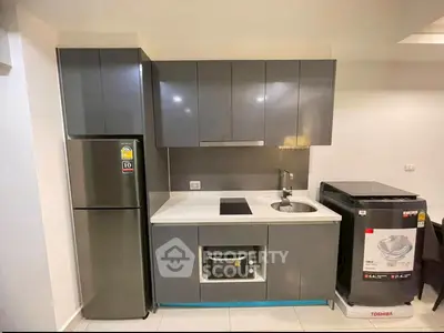 Modern kitchen with sleek cabinets, fridge, and washing machine in compact layout.