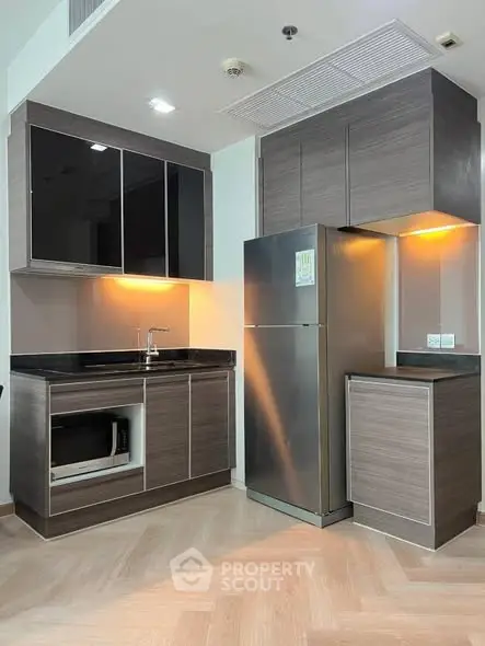 Modern kitchen with sleek cabinetry and stainless steel fridge in a stylish apartment.