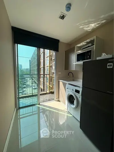 Modern kitchen with washing machine and balcony view in urban apartment
