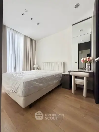 Modern bedroom with elegant decor and natural light, featuring a comfortable bed and stylish furnishings.