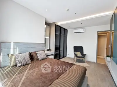 Modern bedroom with stylish decor and ample natural light, featuring a cozy bed and sleek furnishings.