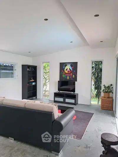 Modern living room with stylish decor and garden view, featuring a cozy sofa and entertainment center.