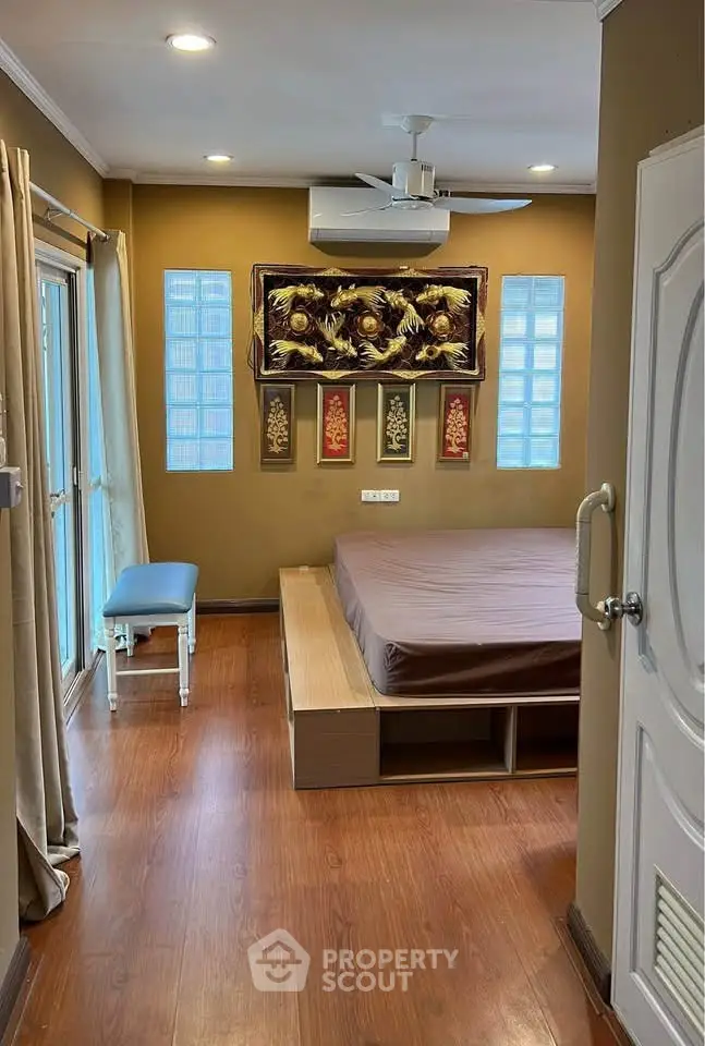 Cozy bedroom with wooden flooring and modern decor, featuring a platform bed and stylish wall art.