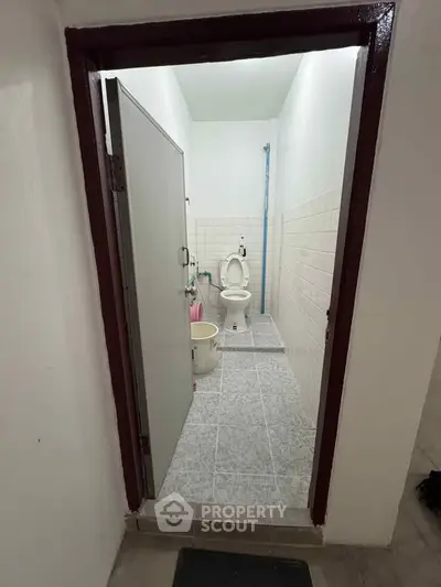 Compact bathroom with tiled floor and basic fixtures, showcasing a simple and functional design.