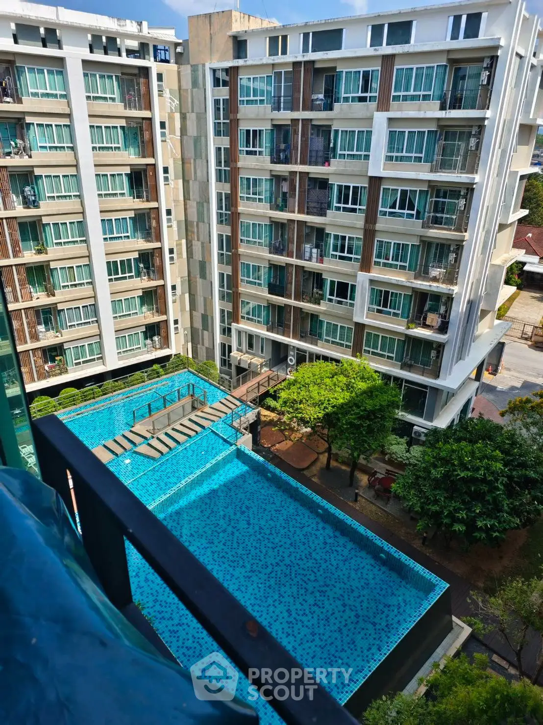 Modern apartment building with pool view and lush greenery