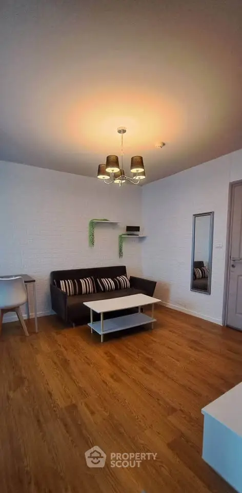 Modern living room with stylish decor and wooden flooring, featuring a cozy sofa and chic lighting.