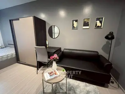 Modern living room with sleek black sofa, stylish decor, and cozy ambiance.