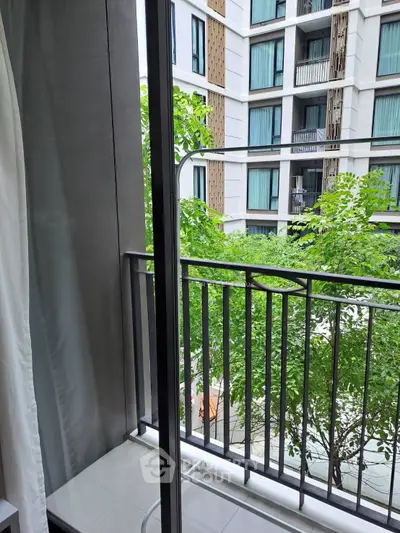 Modern apartment balcony with lush green view and stylish building facade.