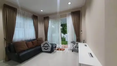 Cozy living room with black leather sofa and garden view