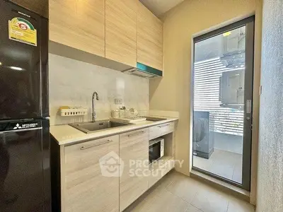 Modern kitchen with sleek cabinetry and balcony access in a stylish apartment.