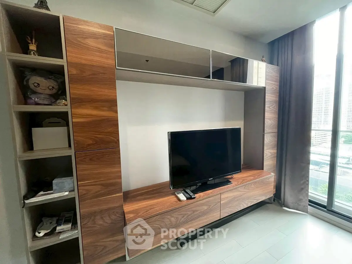 Modern living room with sleek wooden entertainment unit and large window view.