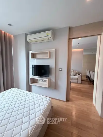 Modern bedroom with wooden flooring, wall-mounted TV, and air conditioning unit.