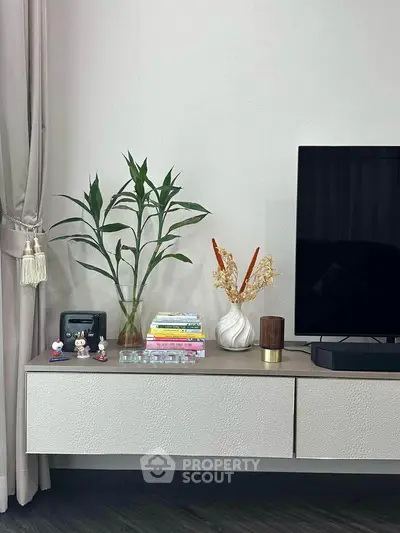 Modern living room with sleek TV stand, decor, and greenery for a cozy ambiance.