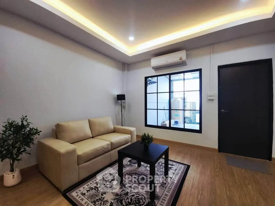 Modern living room with cozy beige sofa, stylish rug, and air conditioning in a contemporary apartment.