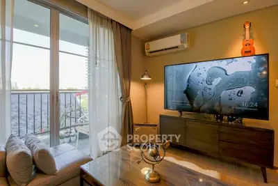 Modern living room with large TV, cozy seating, and balcony view.