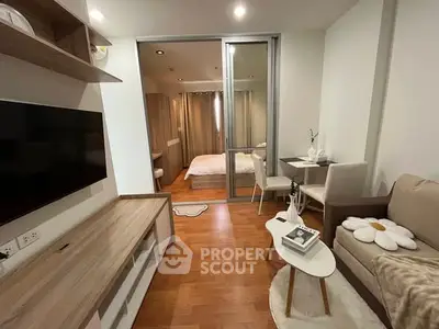 Modern living room with cozy decor and open view to bedroom, featuring wooden flooring and stylish furniture.