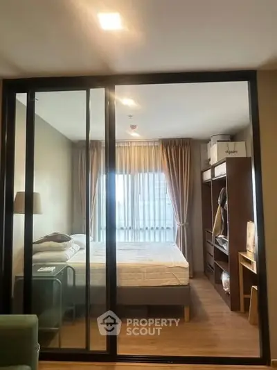 Modern bedroom with glass partition and wooden flooring in stylish apartment.