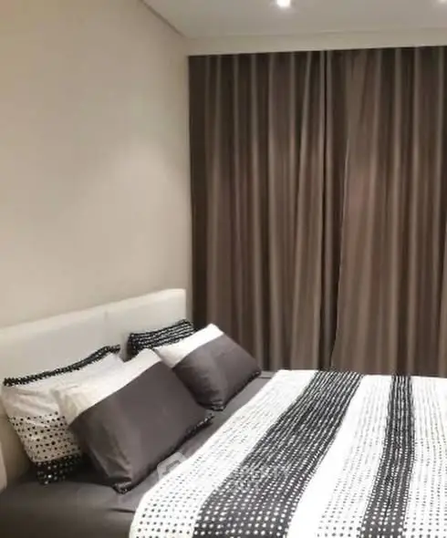 Cozy bedroom with stylish bedding and elegant curtains, perfect for relaxation.