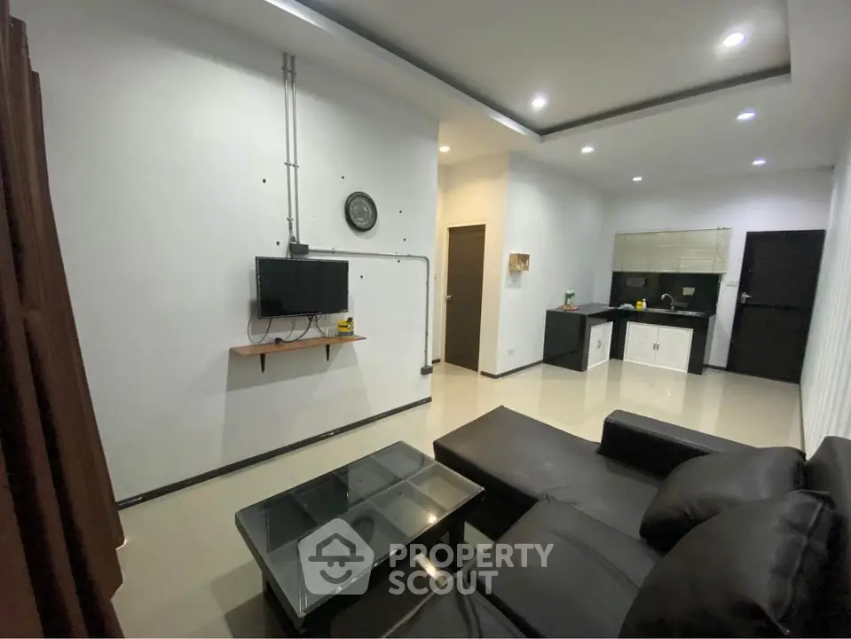 Modern living room with sleek black furniture and open kitchen layout