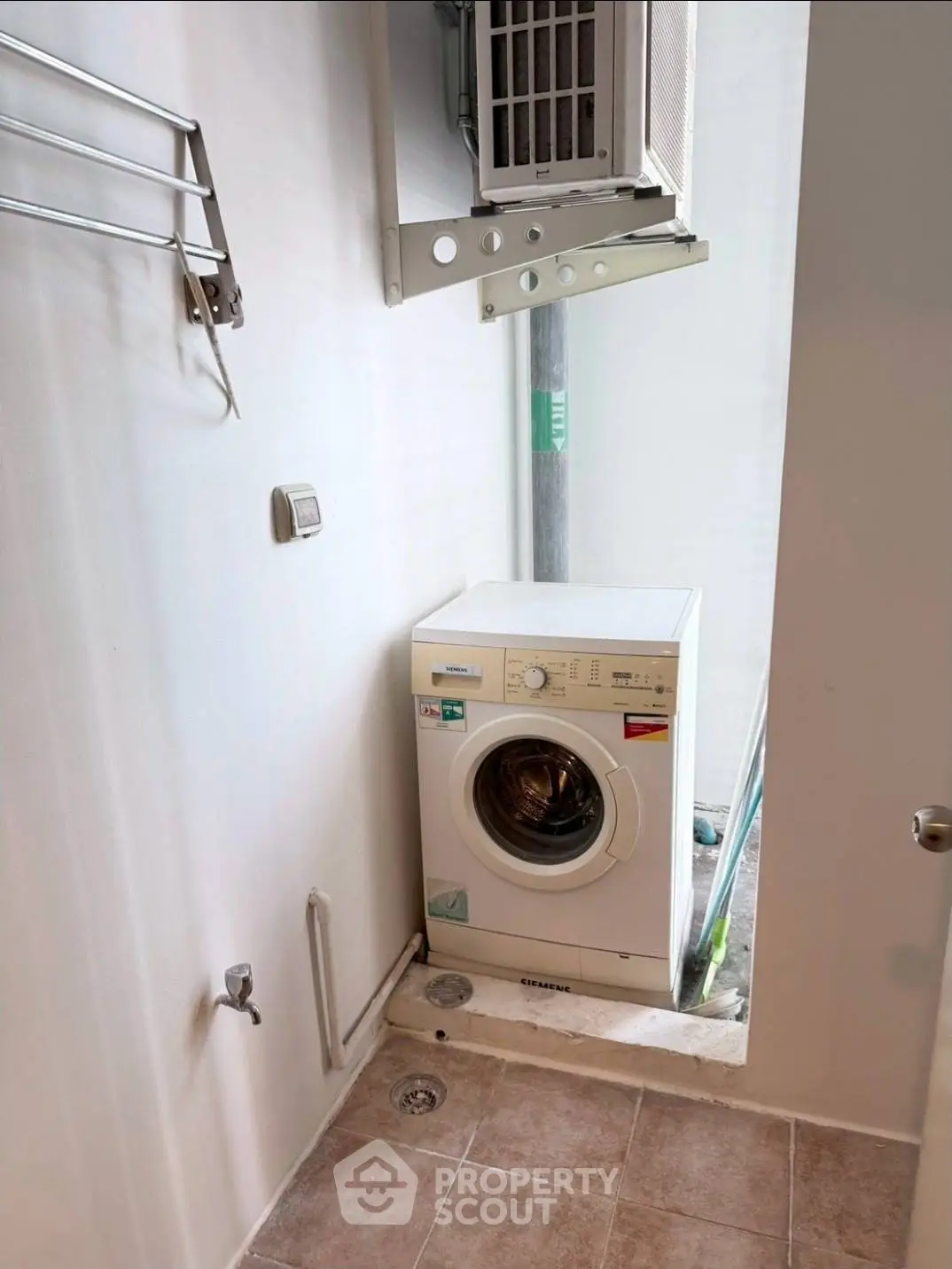 Compact laundry area with washing machine and air conditioning unit in modern apartment.