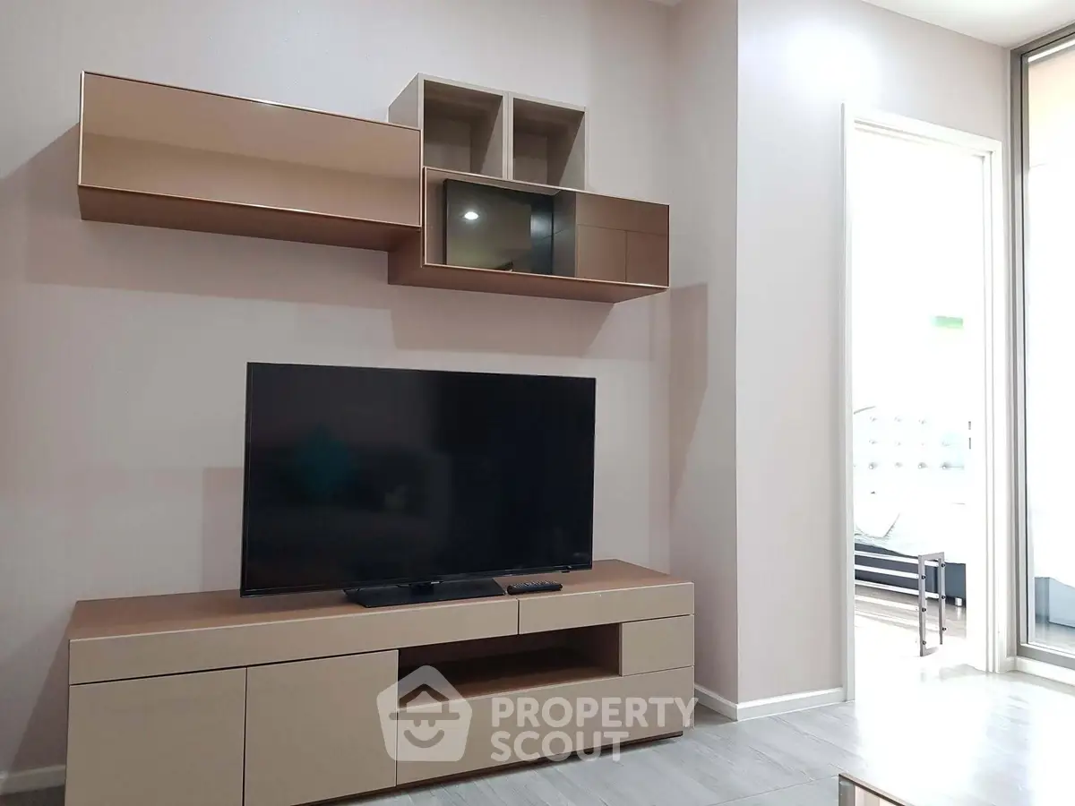 Modern living room with sleek TV unit and wall-mounted cabinets, featuring minimalist design and natural light.