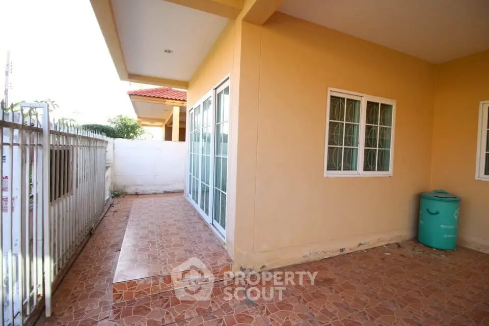 Charming single-story home with tiled patio and large windows, perfect for outdoor relaxation.