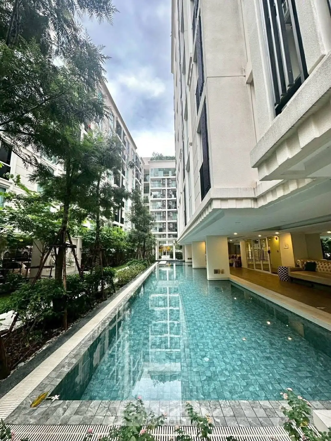 Luxurious residential building with stunning pool and lush greenery.