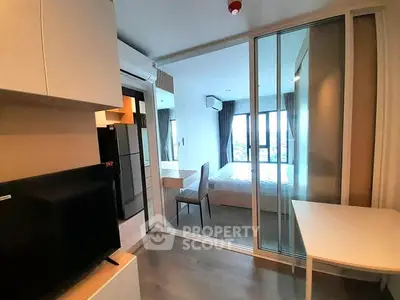 Modern studio apartment with glass partition and sleek furnishings, offering a bright and cozy living space.