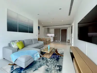 Modern living room with open kitchen, stylish decor, and large TV, perfect for contemporary living.
