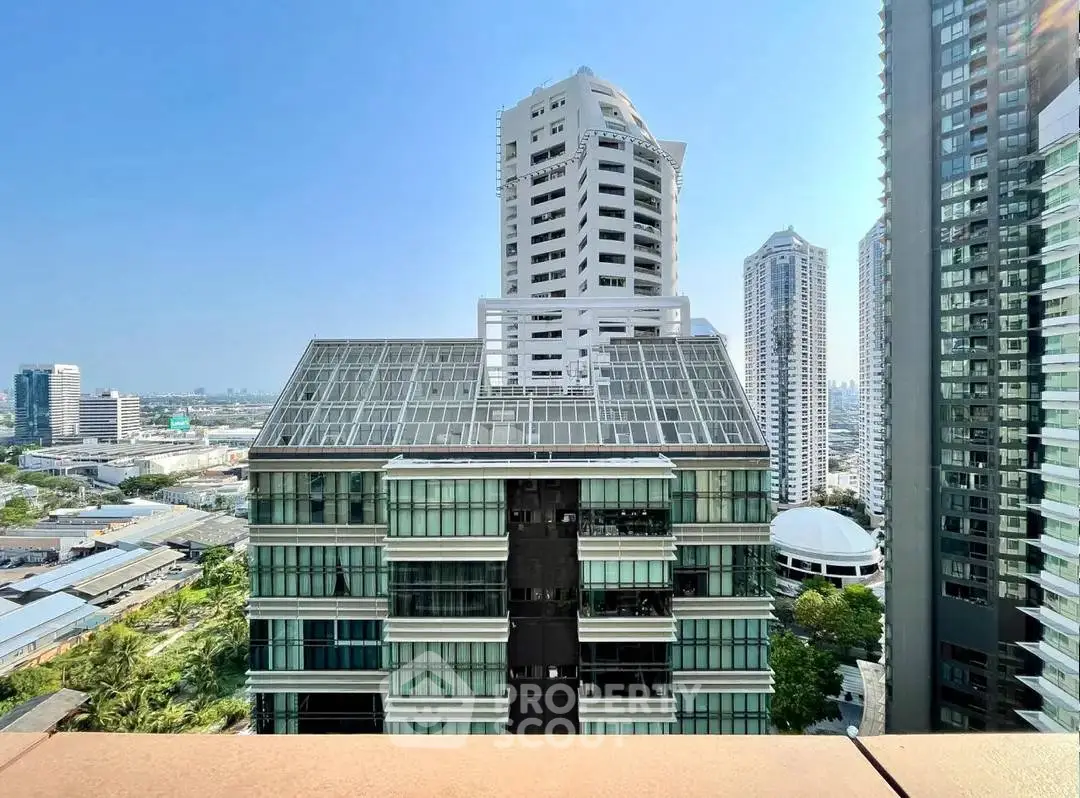 Stunning cityscape view from high-rise balcony with modern architecture and clear blue sky.