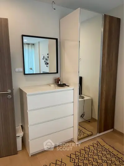 Modern bedroom with sleek wardrobe and dresser, featuring a stylish mirror and wooden accents.