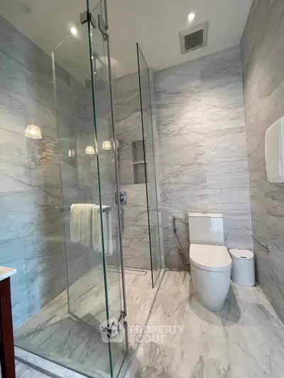 Luxurious modern bathroom with glass shower and marble tiles