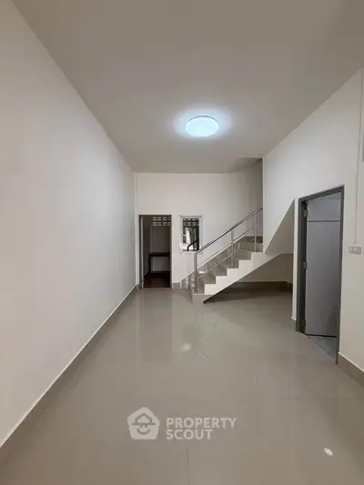 Spacious modern interior with sleek staircase and glossy tiled flooring, perfect for contemporary living.