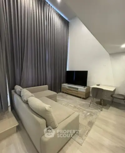 Modern living room with high ceilings, elegant curtains, and cozy seating area.