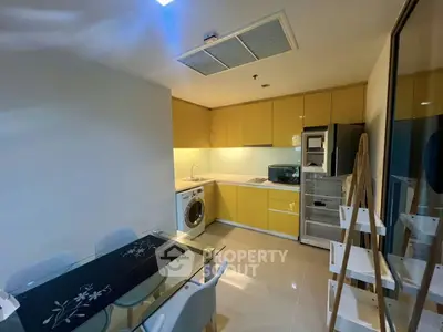 Modern kitchen with yellow cabinets, dining area, and built-in appliances in a stylish apartment.