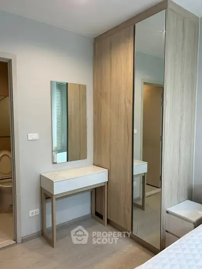 Modern bedroom with sleek wooden wardrobe and vanity mirror, showcasing minimalist design and functionality.