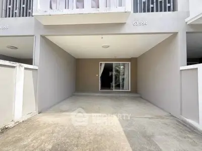 Modern townhouse entrance with covered parking and sliding glass doors.