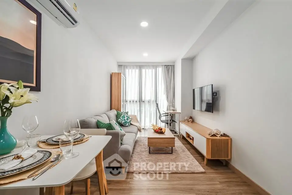 Modern living room with stylish decor and natural light, featuring a cozy sofa and wall-mounted TV.