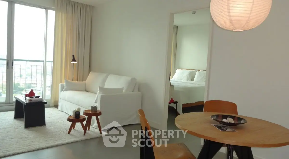 Modern living room with cozy seating and dining area, featuring a view into a stylish bedroom.