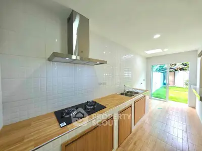 Modern kitchen with gas stove and wooden countertops, featuring a bright open layout and garden view.