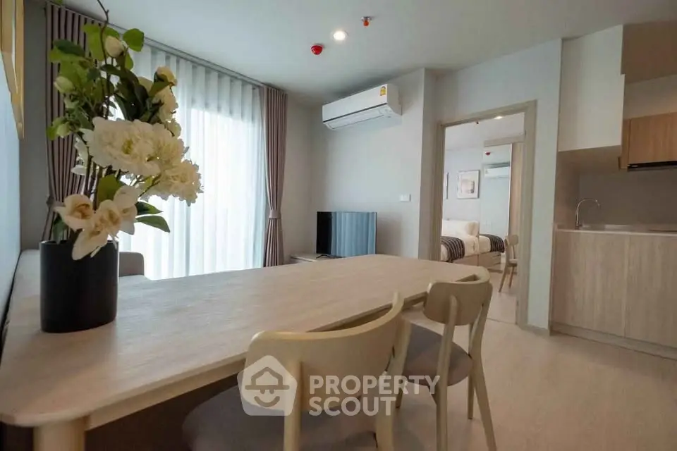 Modern open-plan living room with dining area and kitchen, featuring stylish furniture and natural light.