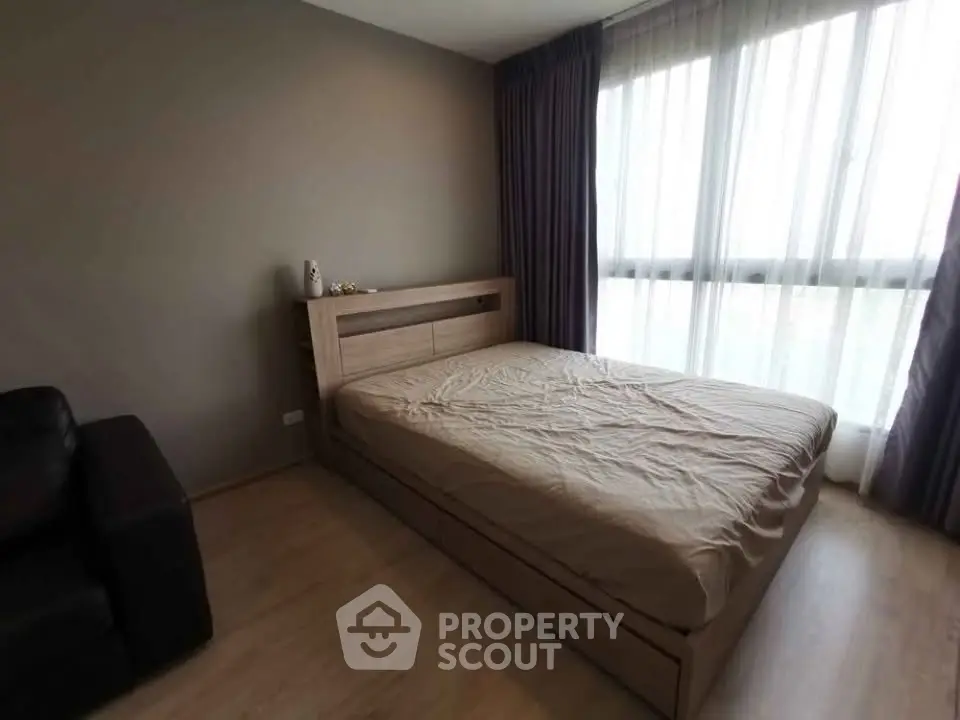 Cozy bedroom with large window and modern furnishings in a stylish apartment.