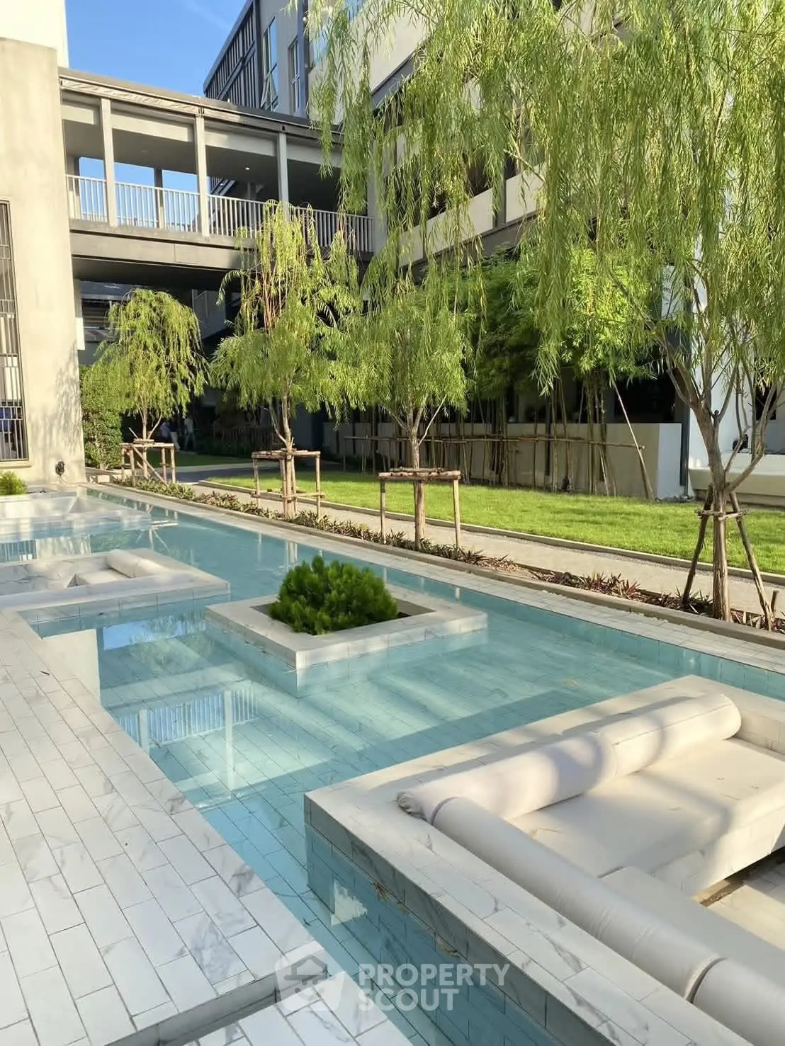 Luxurious modern apartment complex with serene pool and lush greenery