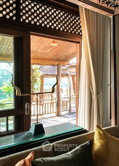 Charming wooden interior with a cozy living space opening onto a serene balcony with lush greenery views, perfect for tranquil living.