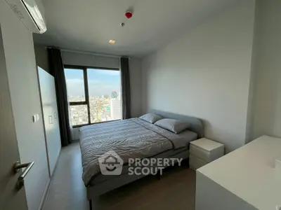 Modern bedroom with city view, featuring a comfortable bed and sleek furnishings.